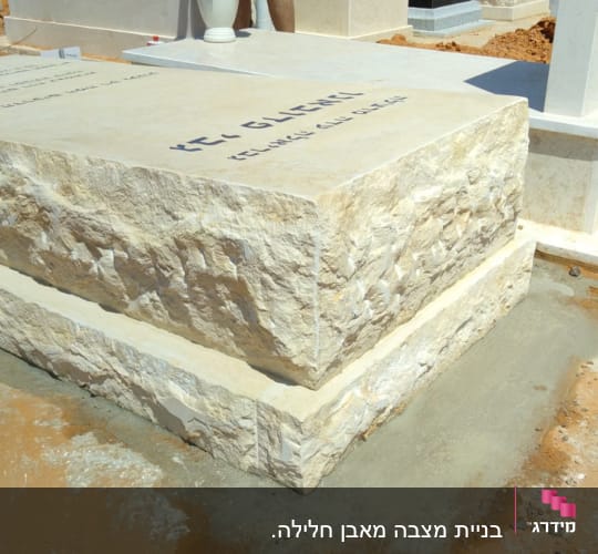 קבר אבן עם כיתוב בעברית ופרחים באגרטל